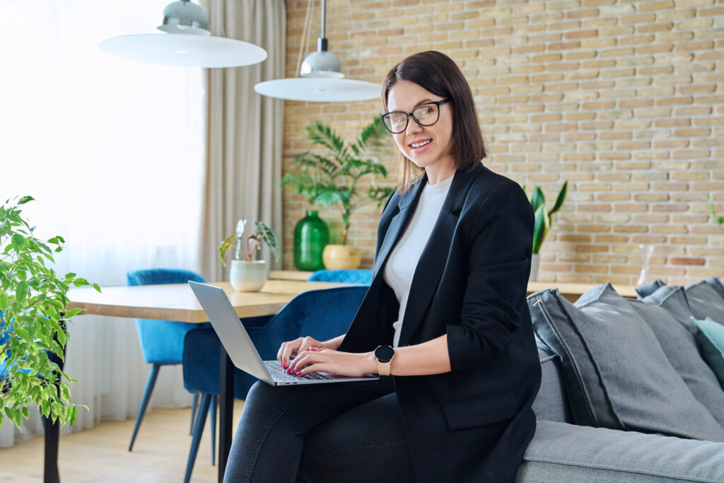 A business professional working on a laptop in a more relaxed office environment.